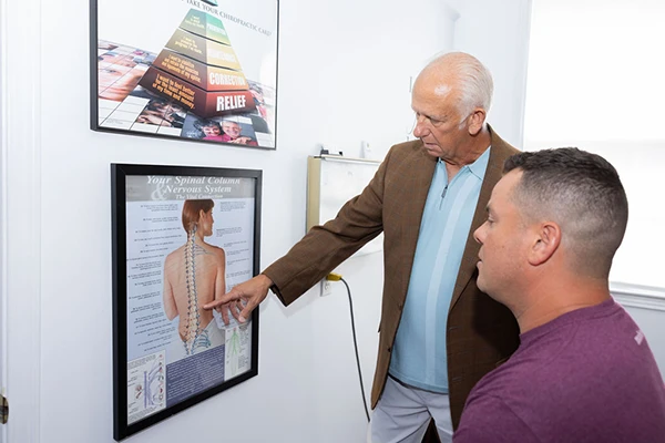 Dr. Donald Ellis pointing to a poster with a spine diagram while consulting with a patient